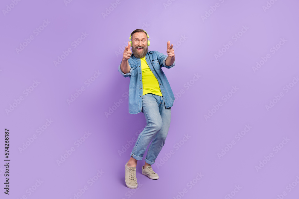 Full body photo of attractive grandpa pointing you cheerful dance headphones wear trendy jeans garment isolated on yellow color background Full body photo of attractive grandpa pointing you cheerful dance headphones wear trendy jeans garment isolated on yellow color background