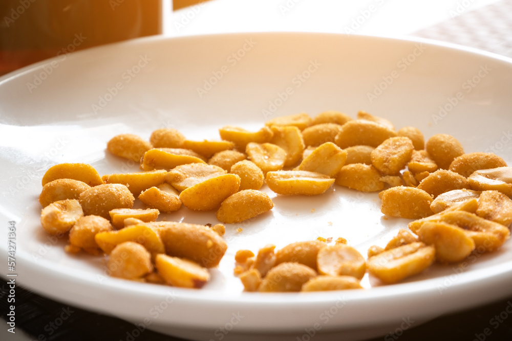 Pile of peanuts with salt and spices on white plate. Tasty snack. Pile of peanuts with salt and spices on white plate. Tasty snack.