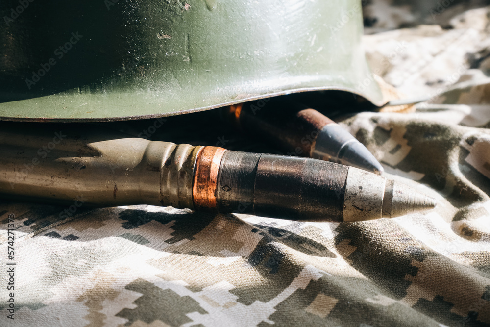 Naklejka premium Bullets and helmet on khaki camouflage background. Lend-Lease and Army concept. Sales of weapons and ammunition. Military industry, war, global arms trade.