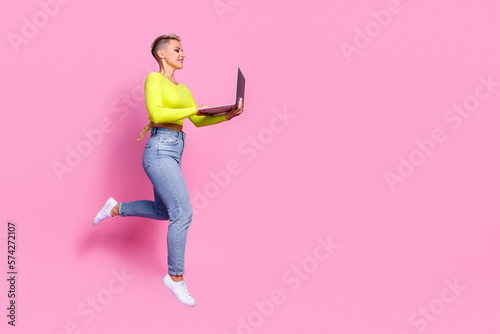 Full size profile photo of attractive active girl jumping run use netbook empty space isolated on pink color background © deagreez