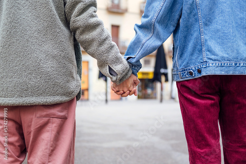 closeup of the clasped hands of a couple of gay men walking on the street, concept of freedom and love between people of the same sex