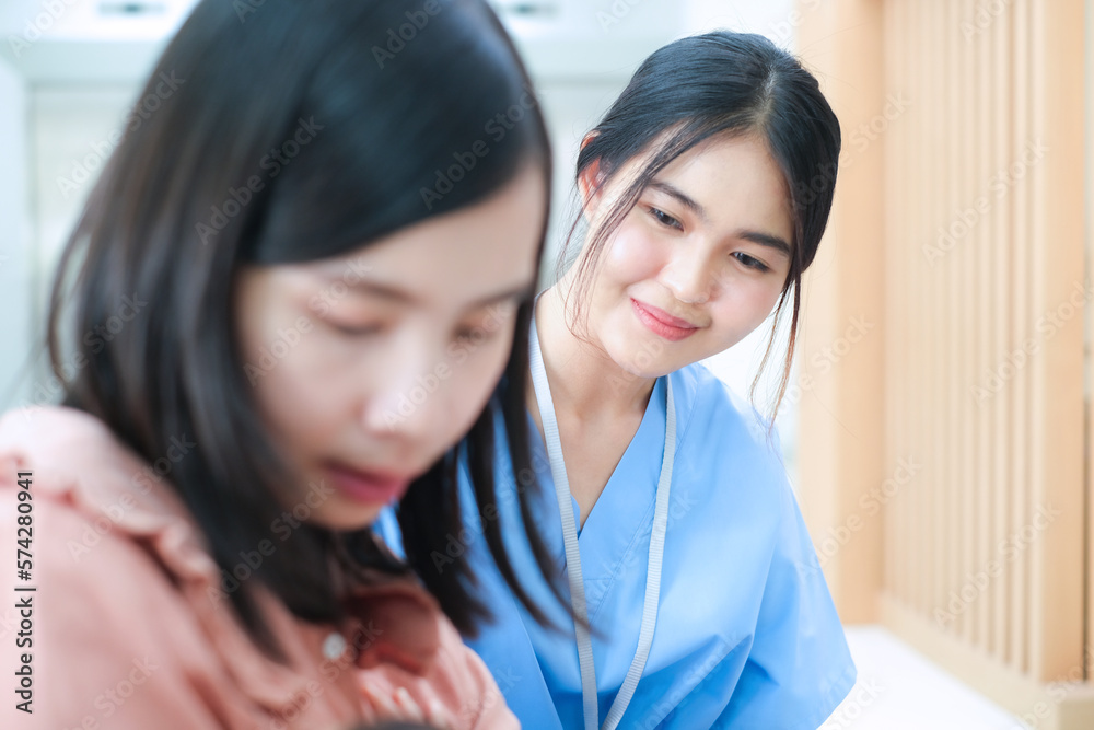 Young asian doctor in uniform take care of mother sitting and breastfeeding her little daughter in hospital.Expertise medical care and health person. Young asian doctor in uniform take care of mother sitting and breastfeeding her little daughter in hospital.Expertise medical care and health person.