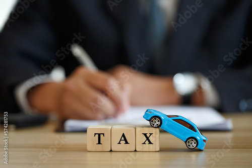 Car tax concept. close up tax wooden text with a toy car. saving money for transport, Man signing car insurance documents or lease papers. Writing signature on contract or agreement.