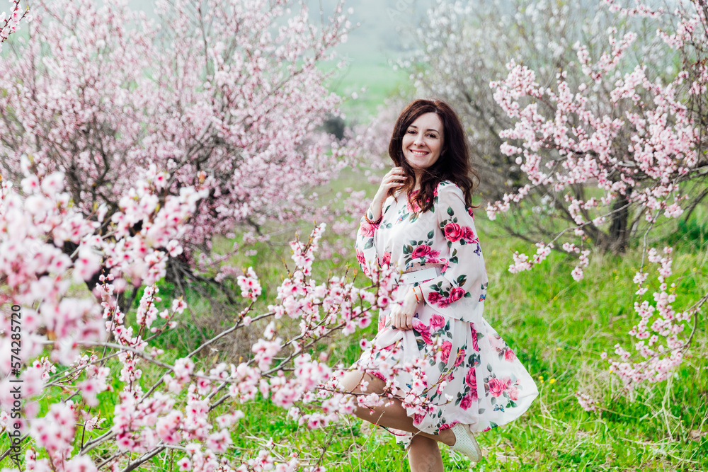 a beautiful woman in flowering trees walks in a park on the street a beautiful woman in flowering trees walks in a park on the street