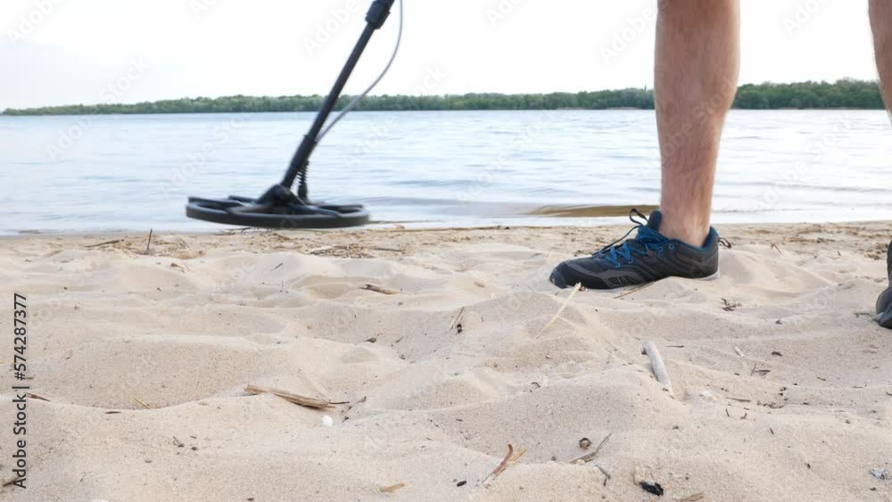 Close-up of a search on the sand with a metal detector. Metal detector coil. Close-up of a search on the sand with a metal detector. Metal detector coil.