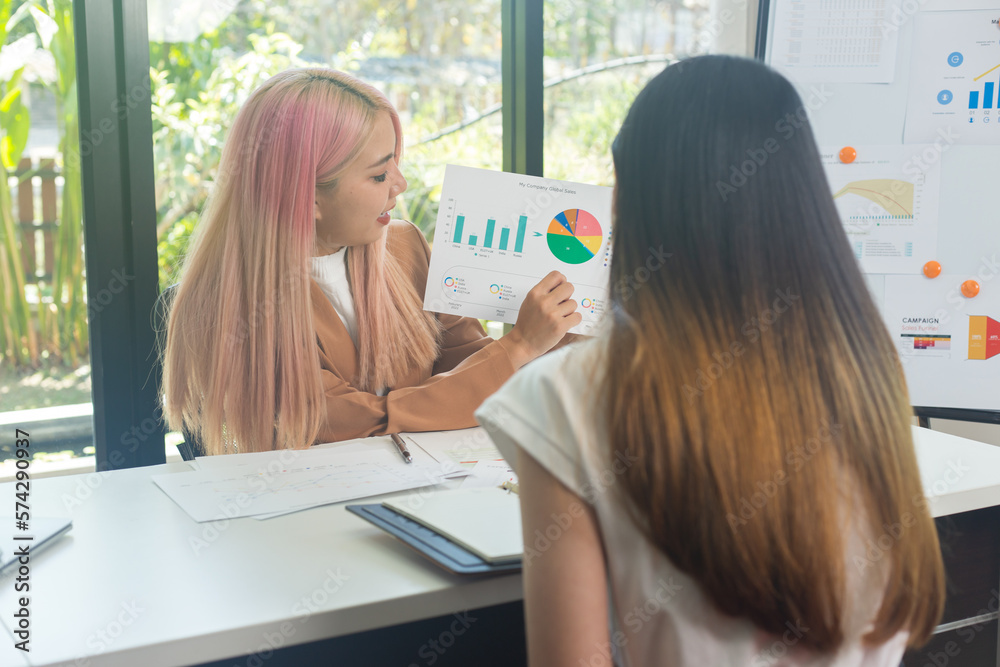 Fototapeta premium Two women analyzing documents while sitting on a table in the office
