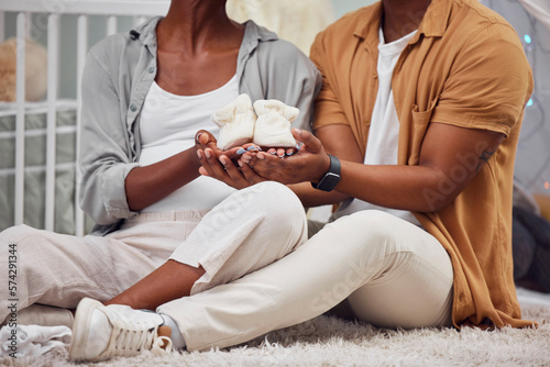 Pregnant, baby shoes and black couple hands to start a new family on bedroom floor. Man and woman together excited about pregnancy future, love and life insurance for health and support in their home