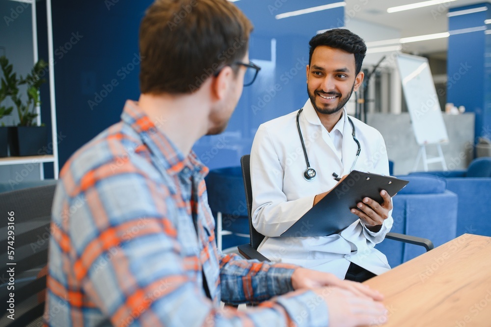 Indian doctor in white gown seeing patients in office. Indian doctor in white gown seeing patients in office.