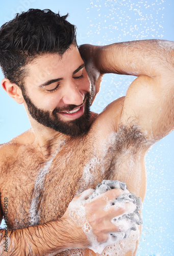 Showering, man and foam with arm pit, cleaning and skincare for dermatology and wet body against blue studio background. Male, gentleman and morning routine for daily hygiene and grooming on backdrop