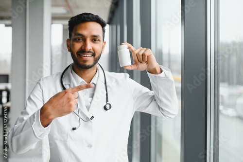 Handsome Indian Male Doctor holding empty white or blank dropper bottle