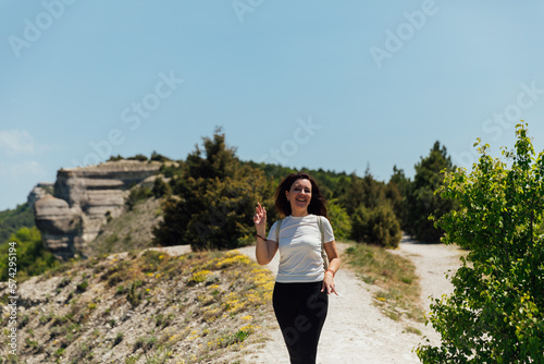 cheerful woman in sportswear goes on a hike walk in the mountains