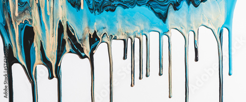 Liquid ink flows down white canvas. Fluid art background with mix of light blue and golden tints. Acrylic paints flows to down. Cyan gold abstract backdrop. Mixing of glitter colors. Aqua with gilding