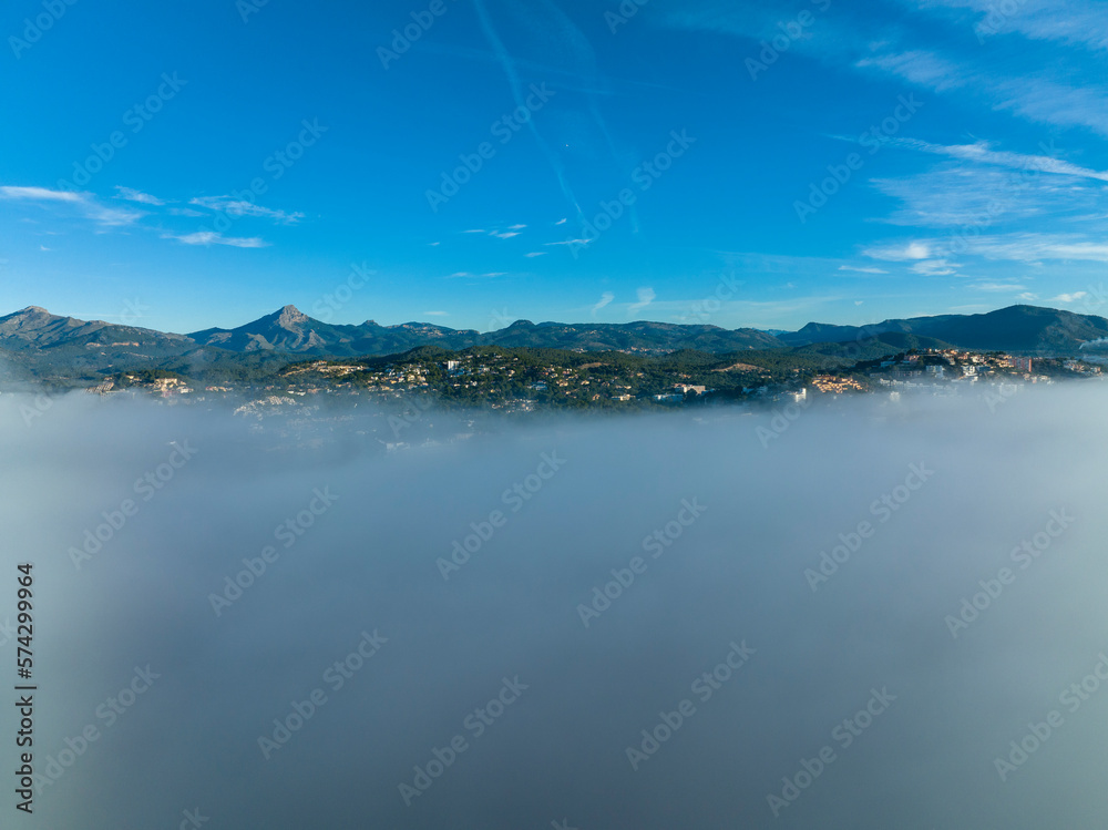 Aerial view, flight above the clouds, the coast of Mallorca in the fog with the town of Santa Ponca, Mallorca, Spain