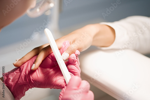 Nail artist in beauty salon making manicure for client. Professional polish nails by tool. Concept of nails, feet health and podiatrist profession 