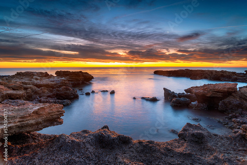 Beautiful sunrise over rocks at the beach at Torre de la Sal