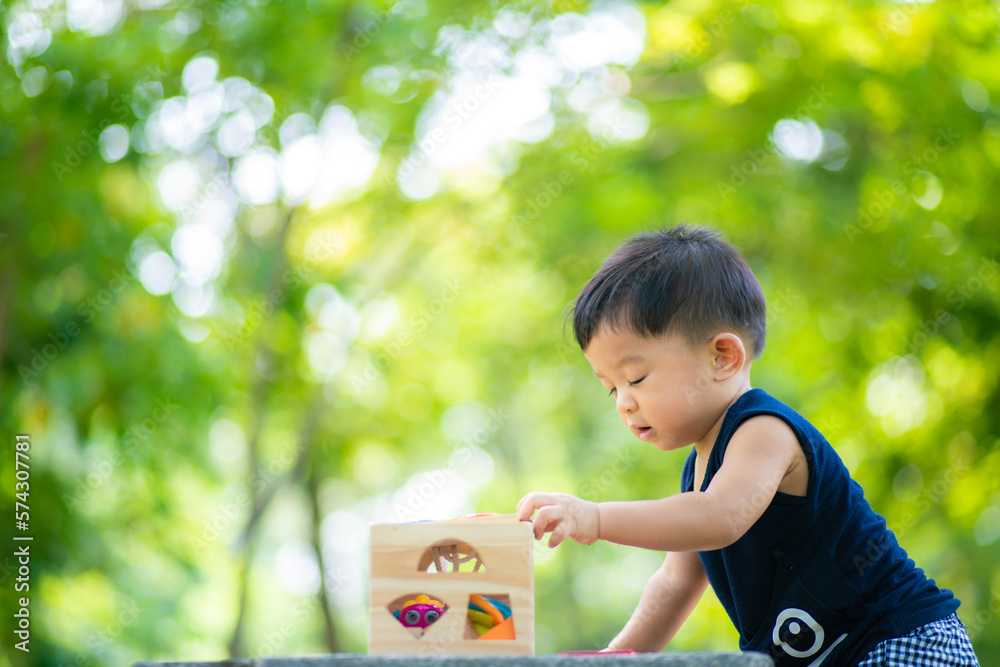 Toddler asian boy playing wooden toy in city green park Toddler asian boy playing wooden toy in city green park