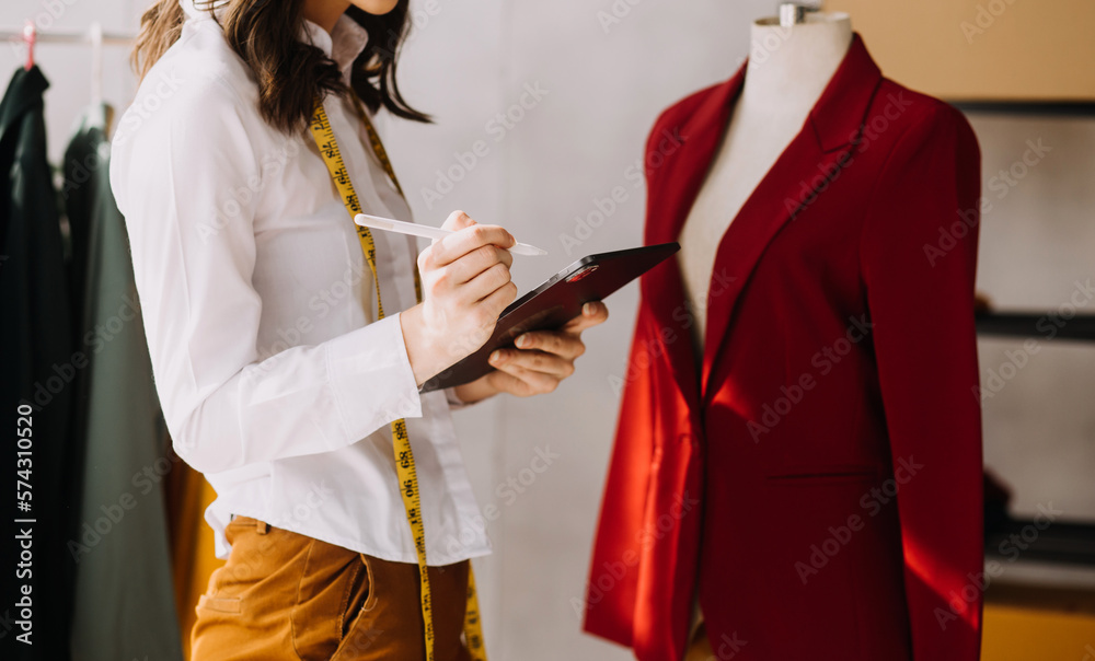 Fototapeta premium Fashion blogger concept, Young women selling clothes on video streaming.Startup small business SME, using smartphone or tablet taking receive and checking in studio