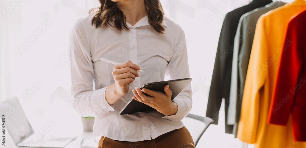 Obraz premium Fashion blogger concept, Young women selling clothes on video streaming.Startup small business SME, using smartphone or tablet taking receive and checking in studio