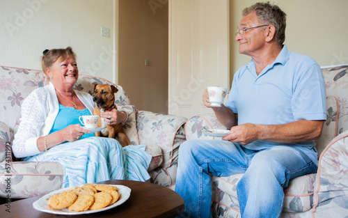 Retirement: Time for Tea. A senior couple and their dog relax together with tea and biscuits, a British tradition. From a series of related images.