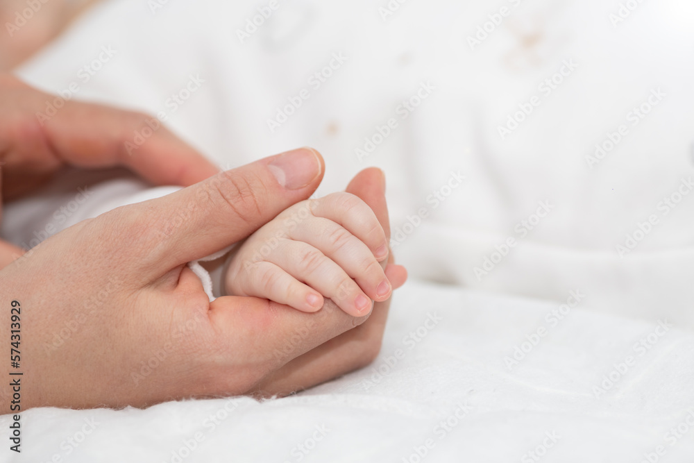 Close up mother holding tiny hand of little newborn baby boy girl, helping hands, bonding different generations. Happy motherhood concept. Close up mother holding tiny hand of little newborn baby boy girl, helping hands, bonding different generations. Happy motherhood concept.