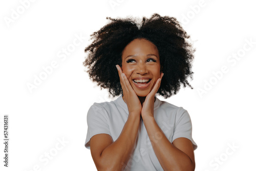 Joyful young dark skinned woman feeling happy, smiling at camera and touching cheeks with both hands