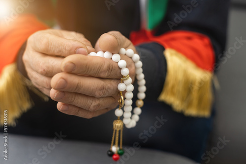 an elderly man prays with a rosary and the flag of the United Arab Emirates photo