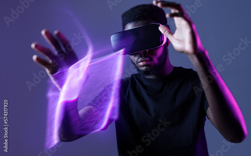 African American guy in Smart glasses of virtual reality. Augmented reality game, future technology, AI concept. VR. Neon light. © KDdesignphoto