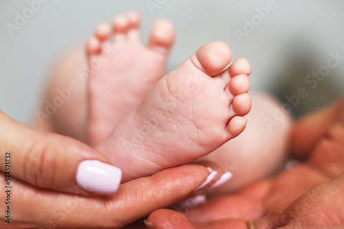 Parents holding newborn baby feet close up on white background © stopabox