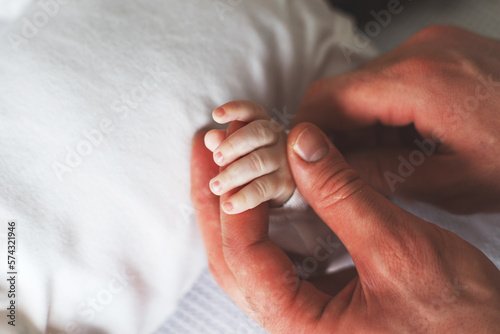 Close up photo of father holding newborn baby hand.