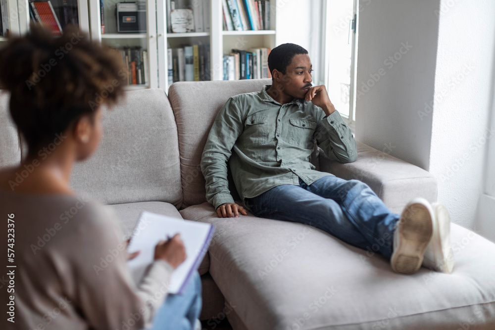 Frustrated african american man reclining on couch at psychologist office