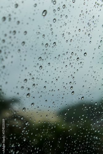 Close-up of the raindrops on car window  and blurred trees are in the background.