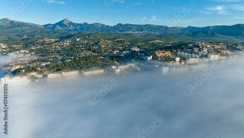 Aerial view, flight above the clouds, the coast of Mallorca in the fog with the town of Santa Ponca, Mallorca, Spain