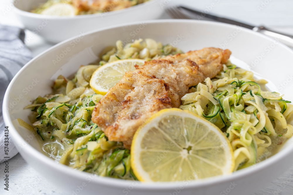 Low carb fish fillet with creamy zucchi noodles on a plate Low carb fish fillet with creamy zucchi noodles on a plate
