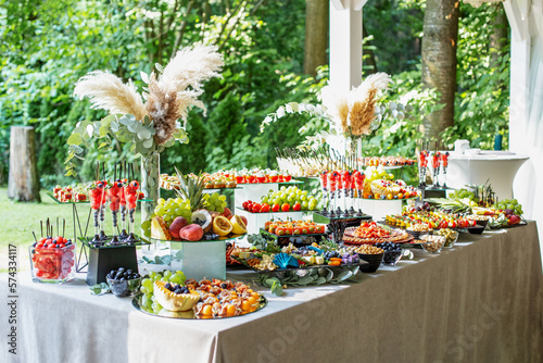 catering buffet table with snacks and appetizers. Set of varios fruits and berries. Decorative vase photo