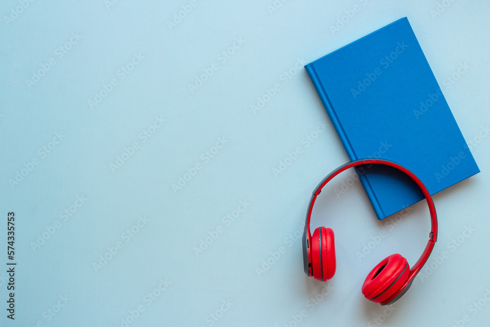 Book and headphones nearby. Lesten to audiobook or podcast concept Book and headphones nearby. Lesten to audiobook or podcast concept
