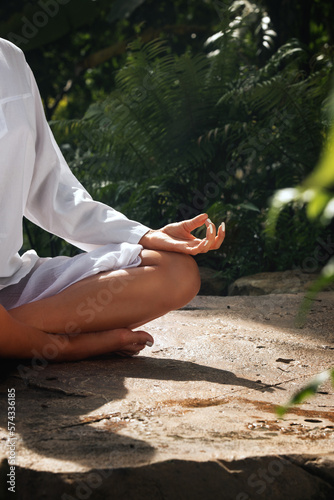Fragment like image of young woman practicing yoga in tropic environment