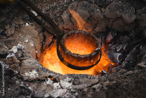 Liquid bronze is being heated to 1200°C. Casting bronze jewelry, Celtic Metalsmith. Experimental Archaeometallurgy. Viking Metal Casting. Bronze Age Forging. The lost-wax method, charcoal-fired hearth photo