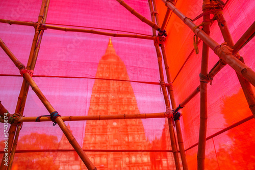 The stupa at Mahabodhi Temple Complex behind red cloth tied with bamboo in Bodh Gaya, India.