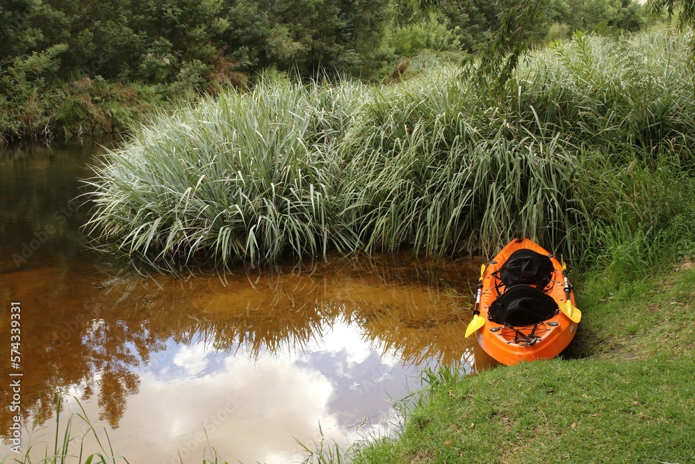 Orange canoe or kayak in calm stream