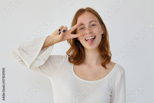 young positive female shows v sign into camera