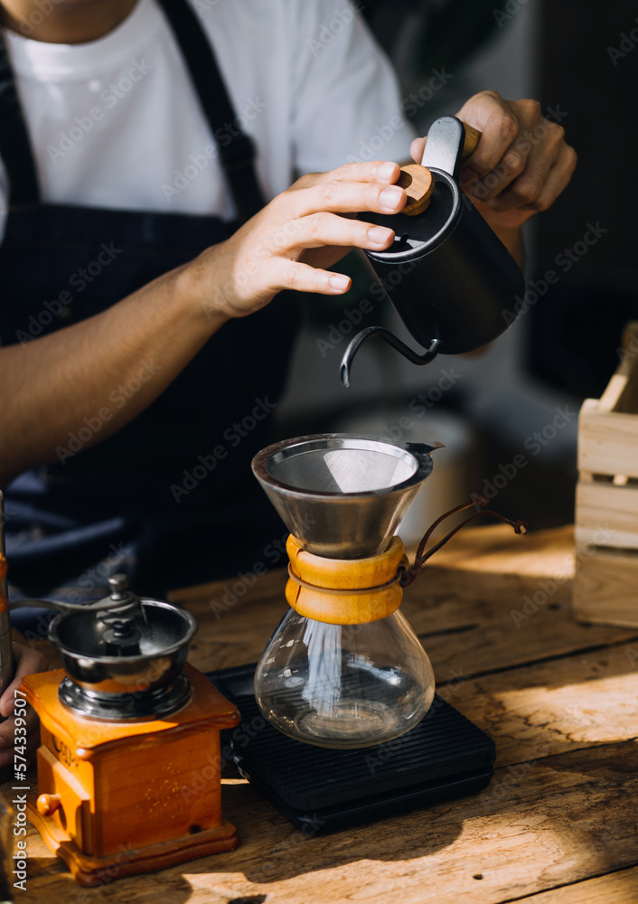 Professional barista preparing coffee using chemex pour over coffee maker and drip kettle. Alternative ways of brewing coffee. Coffee shop concept.