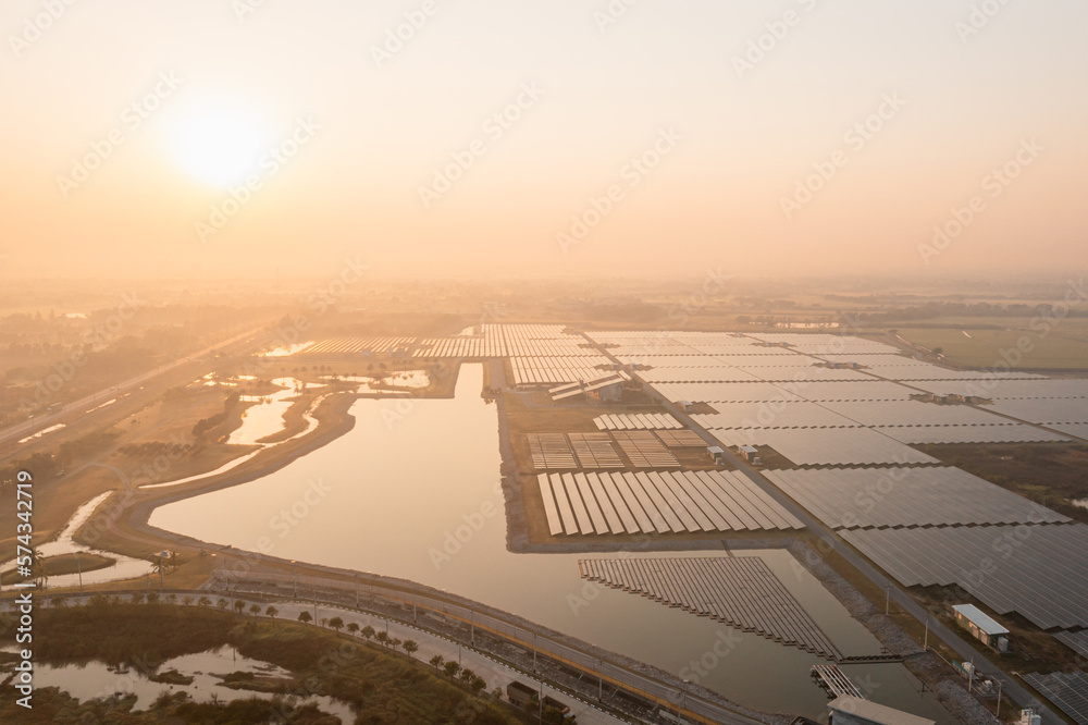 Fototapeta premium Solar Photovoltaic of solar farm aerial view, solar plant rows array of on the water mount system Installation in earthen pond, Floating solar or floating photovoltaics (FPV). Morning scene,