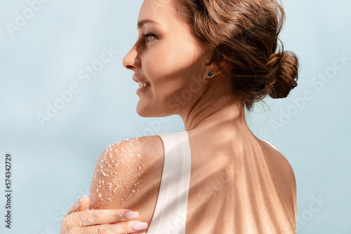 Woman put a natural  white salt scrub to her shoulder