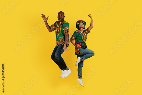 Emotional black couple celebrating success on yellow, gesturing