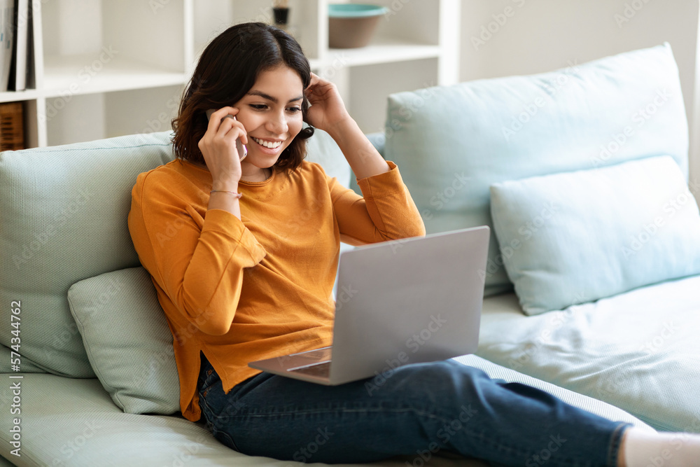 Arab Woman Talking On Cellphone And Shopping Online On Laptop At Home Arab Woman Talking On Cellphone And Shopping Online On Laptop At Home