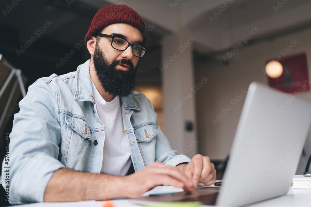 Bearded man working on wireless computer in office Bearded man working on wireless computer in office