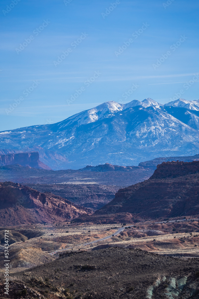 Rock formations with distant snow-covered mountains in the distance in Arches National Park.
