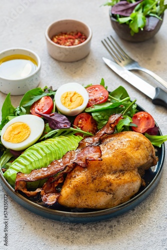 Plate with baked chicken fillet with bacon, fresh vegetables, salad. Popular keto diet, concept of healthy body, food.