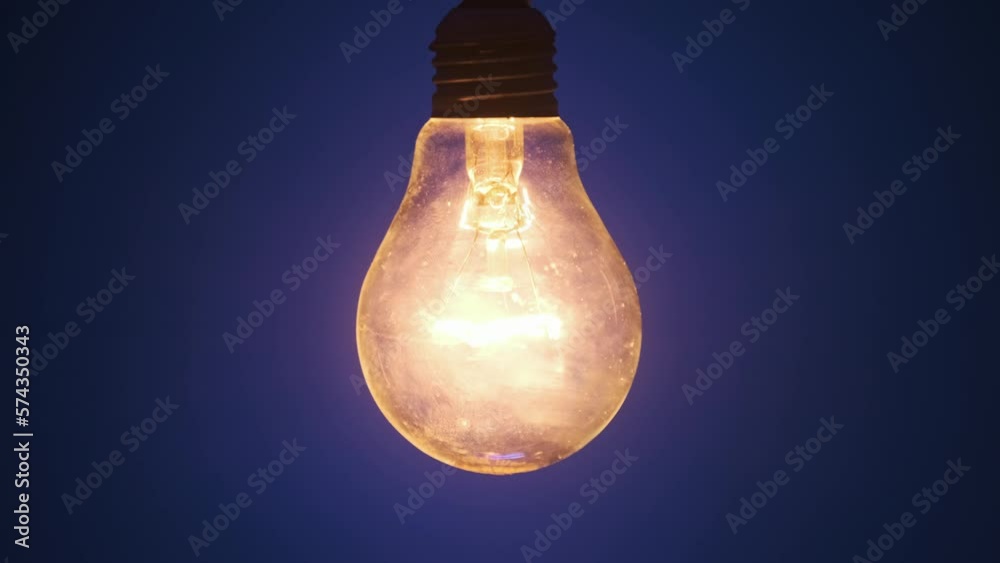 Incandescent lamp lights up and flickers on dark blue background