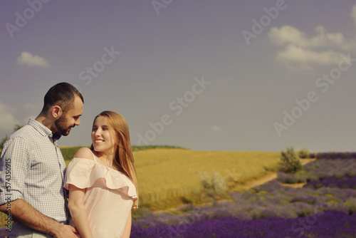 A couple in love in a field of lavender at sunset in good weather. Beautiful woman in a dress with a man on the background of nature, love and feelings. Blue, purple lavender.